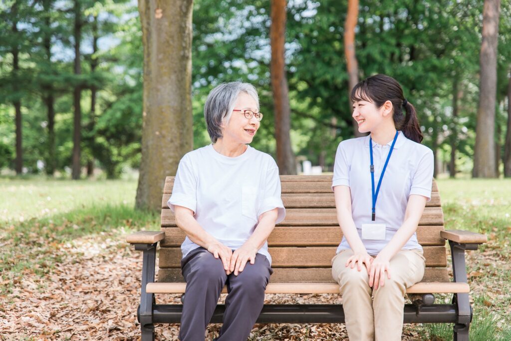 公園で話す高齢者と笑顔の介護スタッフ女性